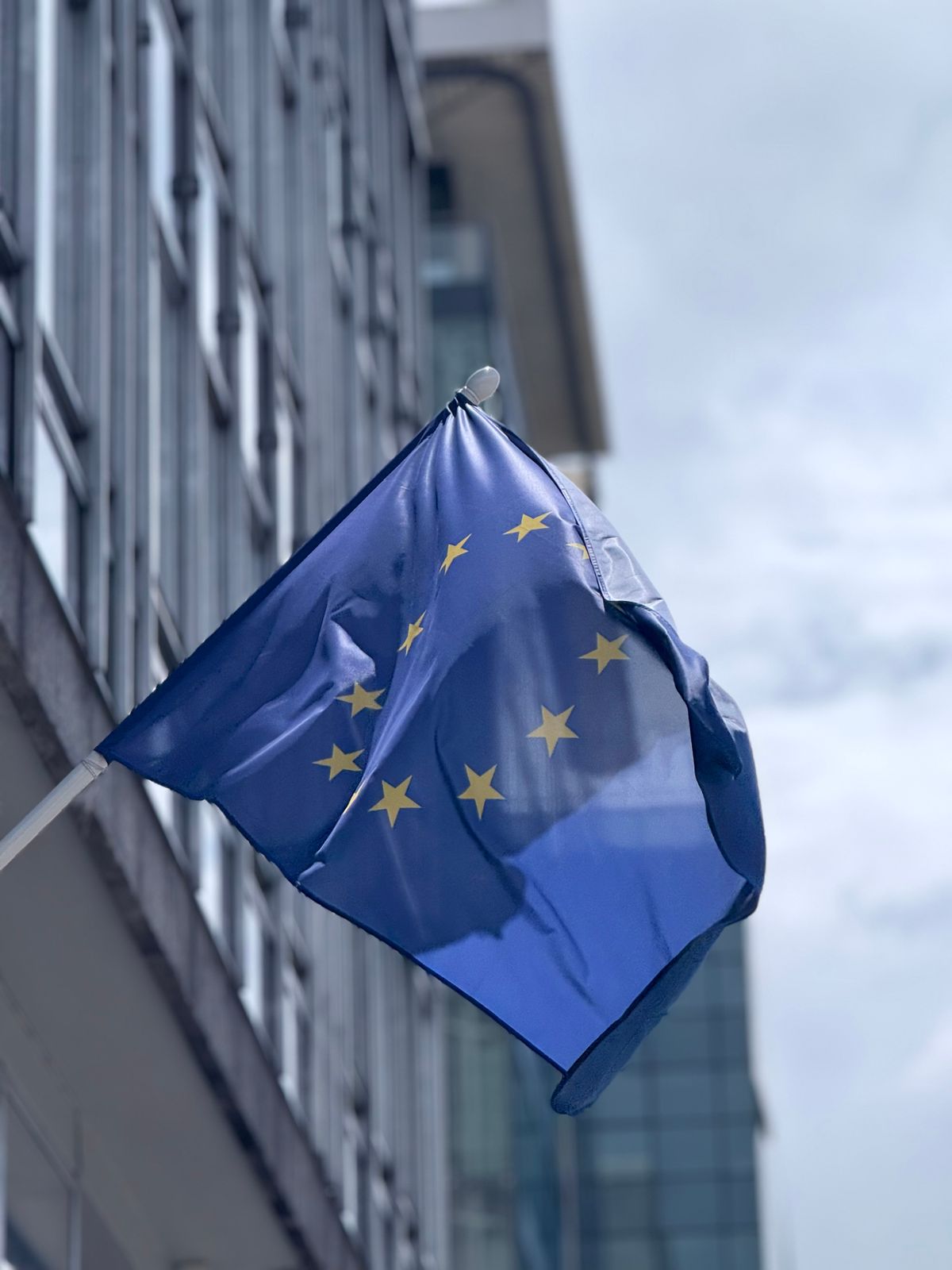 A European Union flag outside a glass-fronted building in Brussels.